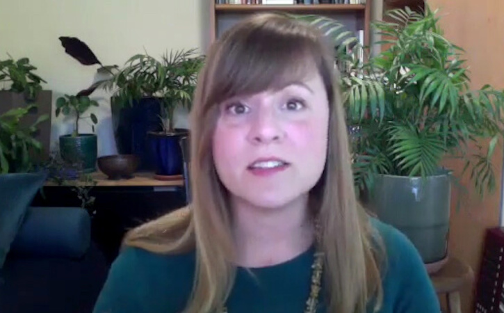 Jennifer Mylander speaking into webcam while seated with plants and a keyboard behind her