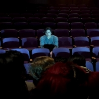 A man sitting in an empty row of theater seats
