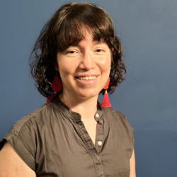 dark haired woman wearing red earring and an olive collared shirt