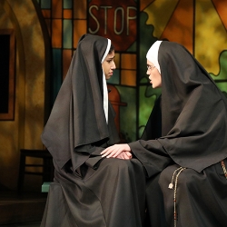 Two women dressed as nuns sitting on a bench having a serious conversation