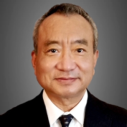 Headshot of Yukihiro Goto dressed in a black suit and tie and looking forward at the camera