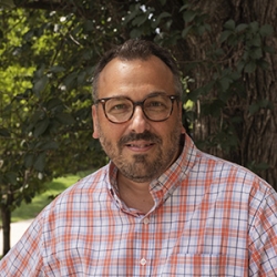 Headshot of Michael Schweikardt, A middle-aged Caucasian man wearing a red-and-white plaid shirt and dark-rimmed glasses
