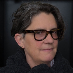 Tracy Ward, a white woman with greying hair and thick, black-rimmed glasses, in three-quarter profile