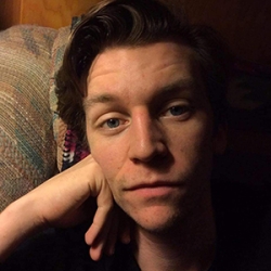 Headshot of Carson Blickenstaff a young white man with dark hair posed with his hand against his cheek