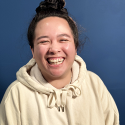 smiling person in a cream colored hoodie