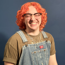 smiling person with eyes closed, bright orange hair and overalls
